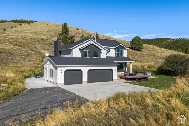Two-story residence with a multi-gabled roofline, attached two-car garage, and an elevated wood-finish deck