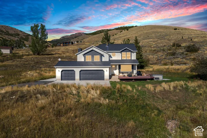 Two-story residence with a three-car garage, expansive wooden deck, and a distinctive circular window detail