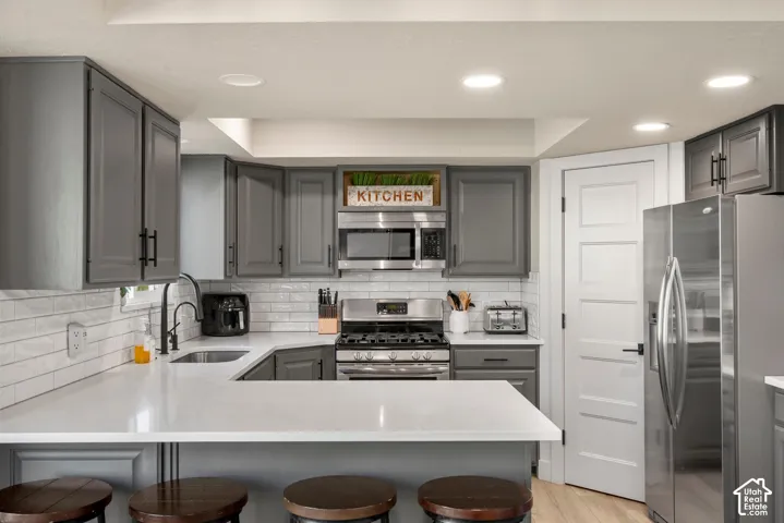 Modern kitchen featuring gray cabinetry, white subway tile backsplash, stainless steel appliances, white countertops, and recessed lighting