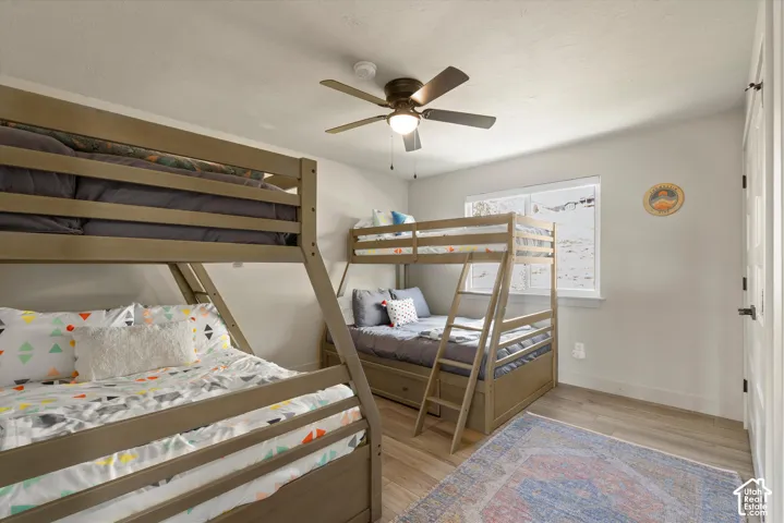Light-toned walls, wood-finish flooring, and a ceiling fan with integrated lighting
