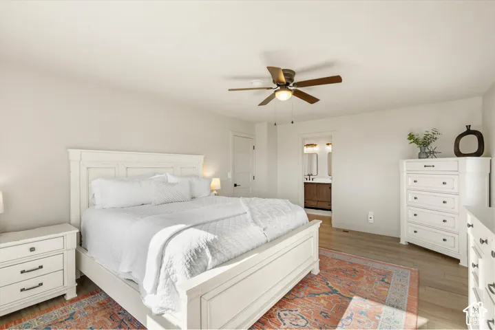 Recessed lighting, ceiling fan with integrated light, wood-finish flooring, white painted walls, and a visible doorway to a bathroom with dual vanity
