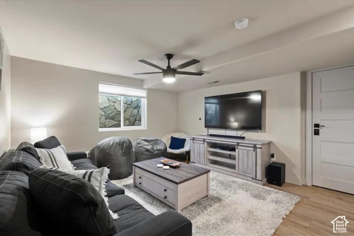 Recessed lighting, ceiling fan, wood-finish flooring, accent window with stone feature, and a four-panel door with matte black hardware