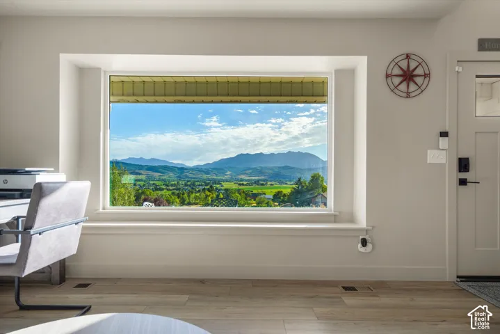 Expansive window with mountain and valley scenery, wide window sill, light wood-finish flooring, and a paneled entry door with black hardware