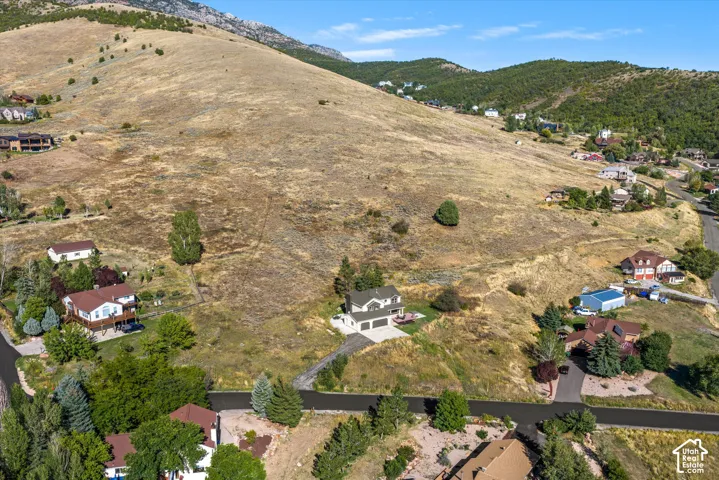 Sloping terrain featuring a two-story residence with an attached garage and paved driveway