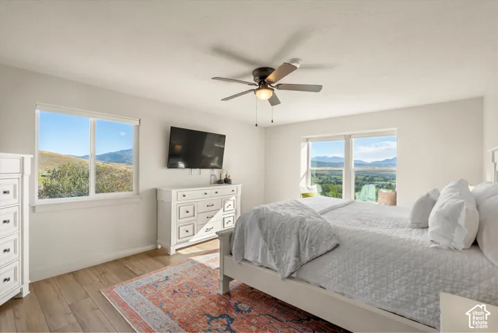 Wood-finish flooring, ceiling fan, and large windows offering expansive mountain and valley scenery
