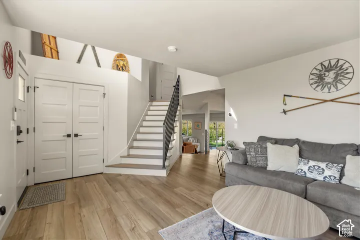 Light wood-finish flooring, white walls, and a staircase with a black metal railing