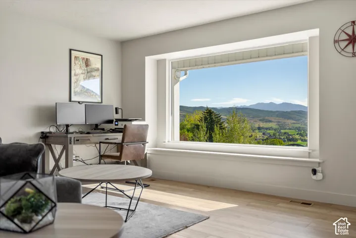 Expansive window providing mountain and valley scenery, light wood-finish flooring, and neutral wall tones