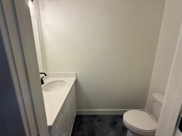 White vanity with a quartz countertop, integrated sink, and matte black faucet