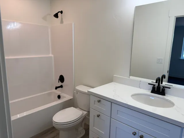 White vanity with a stone-finish countertop, undermount sink, and matte black faucet