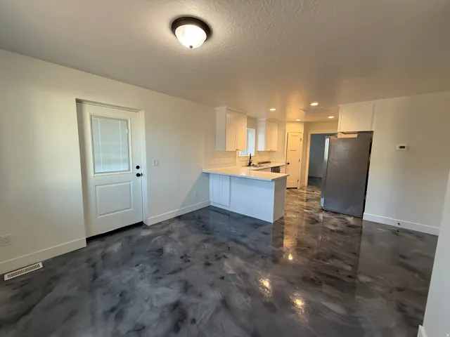 Modern kitchen with white shaker cabinetry, white countertops, stainless steel appliances, recessed lighting, and a unique epoxy floor finish
