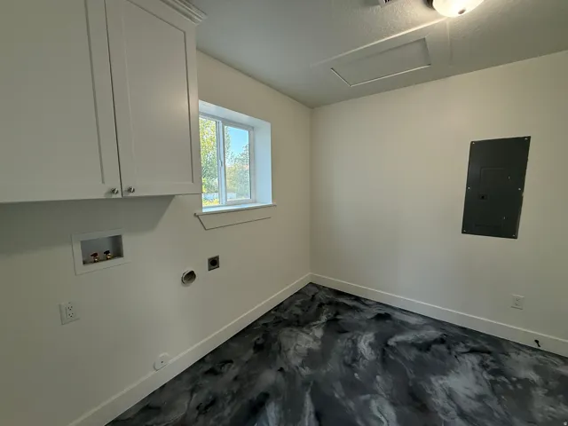 White shaker-style cabinetry, a built-in washing machine hookup, and a window for natural light