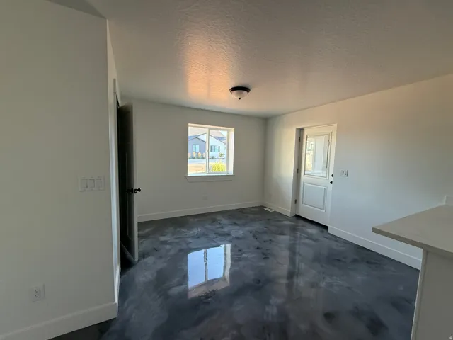 Reflective floor finish, white interior walls, interior door with dark hardware, natural light from a window, and a built-in countertop surface