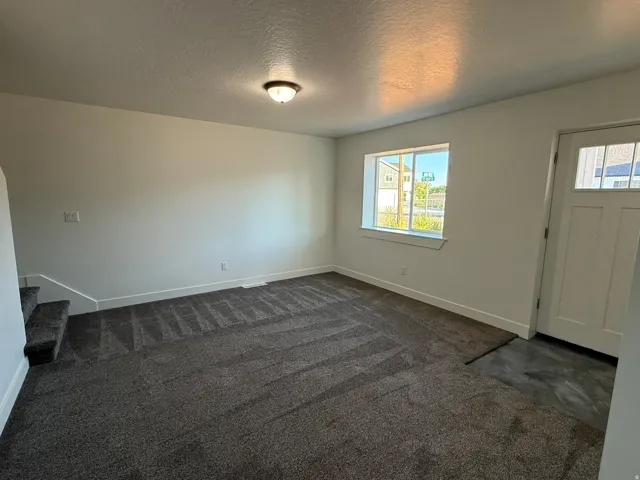 Carpeted living area with white walls, a white front door with window panes, and a flush mount ceiling light