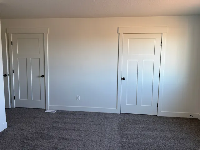 White interior doors with black hardware, white wall paint, and gray carpet flooring