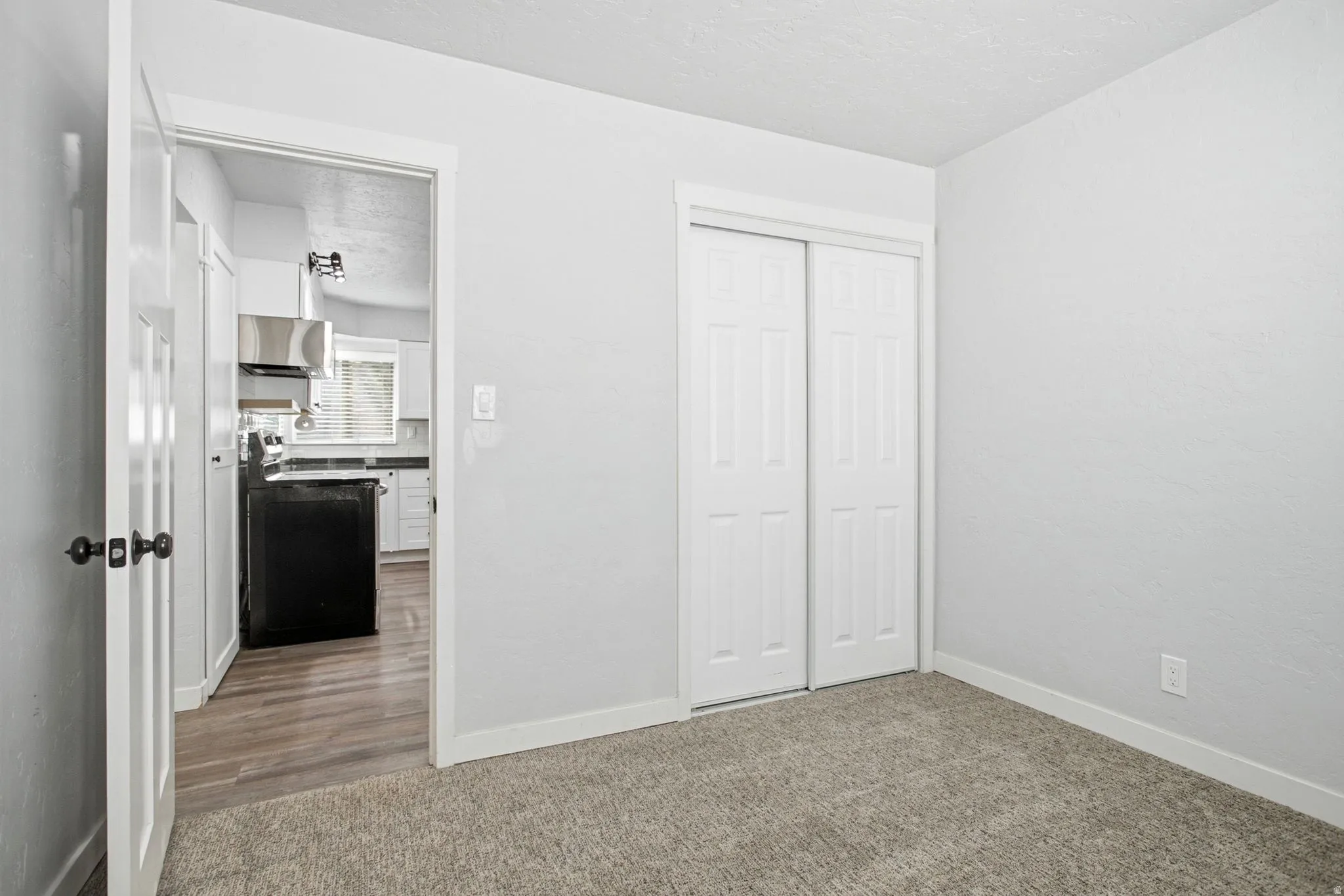 Neutral wall paint with carpet flooring, white trim, and a built-in closet with sliding doors