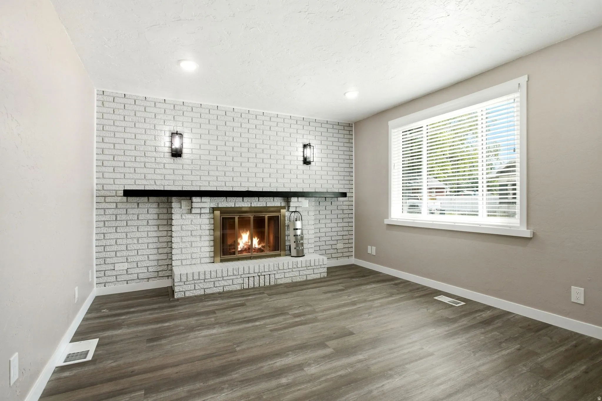 White brick fireplace with a black mantel, brass firebox, and sconce lighting