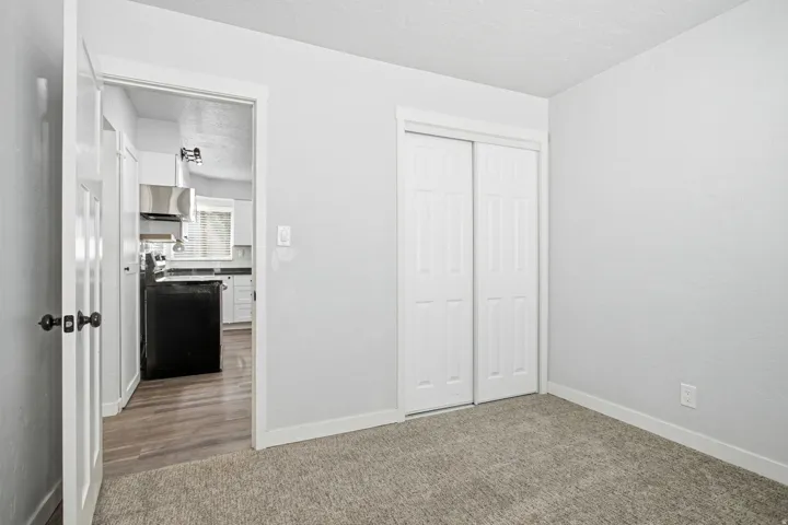 Neutral wall paint with carpet flooring, white trim, and a built-in closet with sliding doors