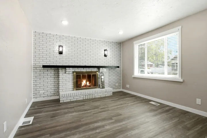White brick fireplace with a black mantel, brass firebox, and sconce lighting