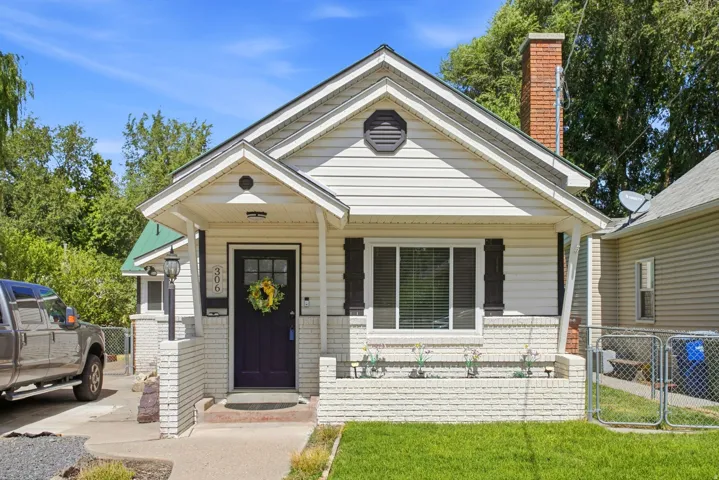 White siding exterior with a covered porch entry, dark front door, and a brick chimney