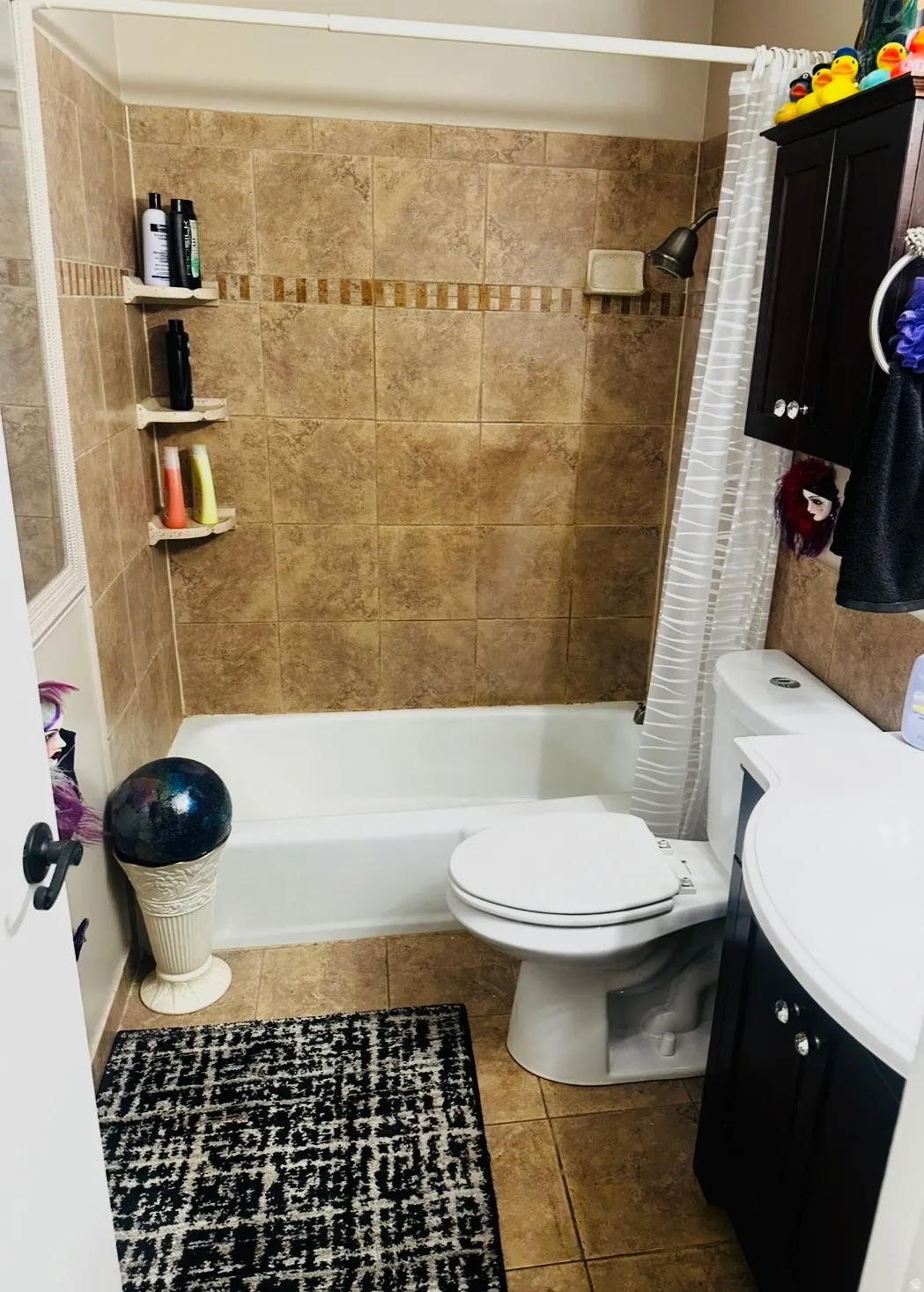 Tiled shower surround with decorative accent band, integrated built-in shelving, and a white bathtub