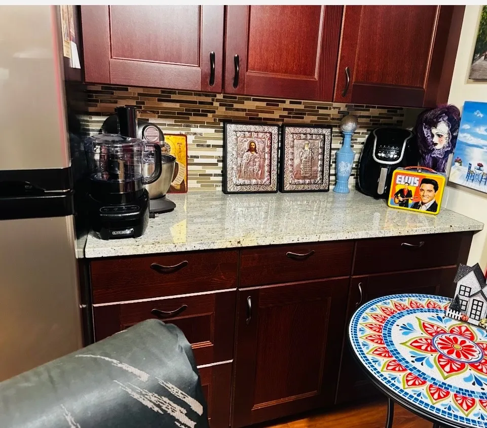 Elegant kitchen featuring rich wood cabinetry with integrated hardware, granite-style countertops, and a decorative tile backsplash in warm earth tones