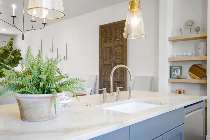 Kitchen island with an undermount sink, gooseneck faucet, light-toned countertop, and blue cabinetry