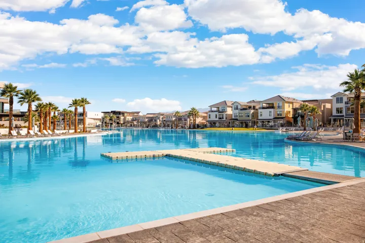 Expansive blue lagoon with a floating dock, bordered by a concrete-finish deck and a row of palm trees
