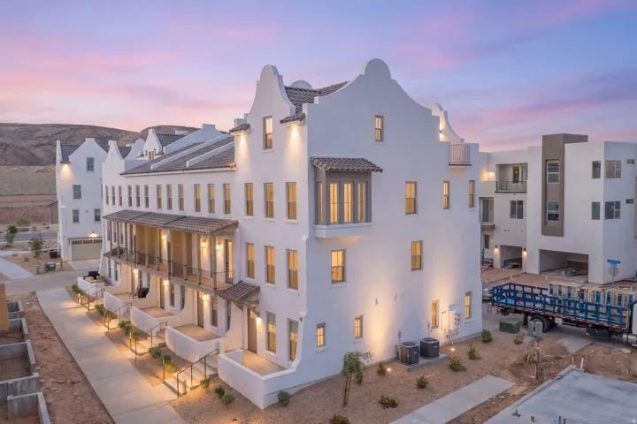 White stucco exterior with an articulated parapet roofline, featuring an upper-level balcony and multiple windows