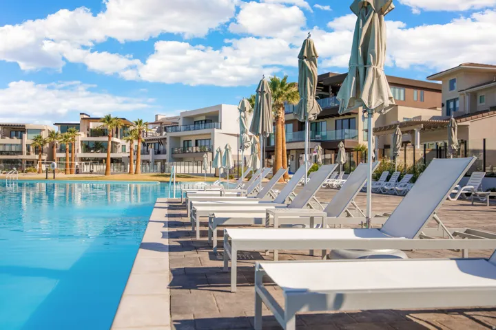 Expansive pool deck with multiple lounge chairs, large pool umbrellas, and a clear blue swimming pool
