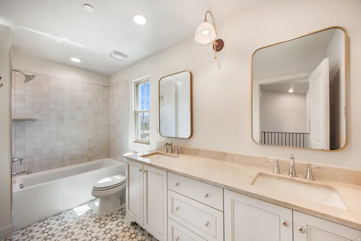 Dual vanity with undermount sinks, light-toned countertop, and gold-framed mirrors