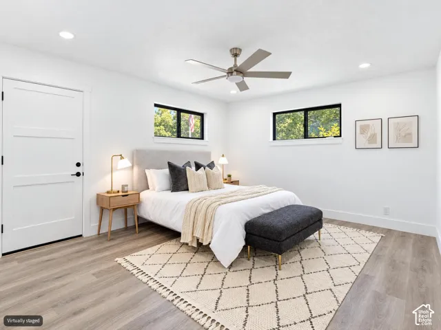 Neutral-toned room featuring wood-finish flooring, recessed lighting, a modern ceiling fan, and windows framed in black
