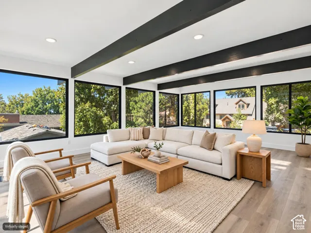 Expansive room featuring exposed ceiling beams, wood-finish flooring, and floor-to-ceiling windows with black frames