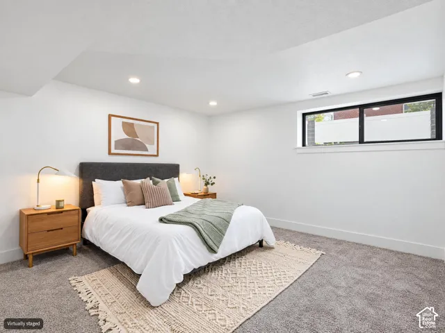 Neutral-toned carpeted flooring, vaulted ceilings with recessed lighting, and a horizontal window featuring a black frame