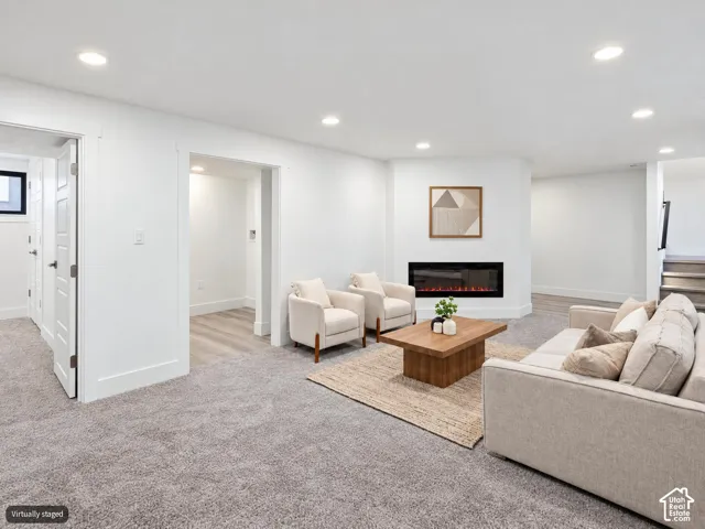 Living area featuring recessed lighting, wall-to-wall carpeting, and a built-in linear electric fireplace