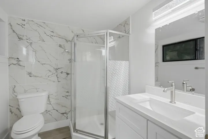 Corner shower with glass enclosure, marble surround, and brushed nickel fixtures