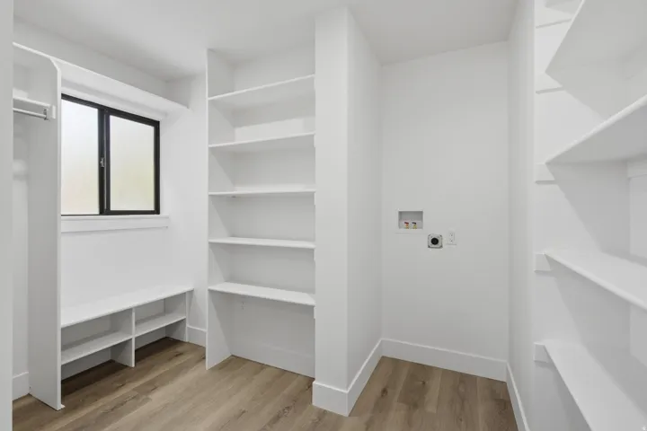 Large walk-in closet with a built-in bench, and electrical outlets for warmers in the winter