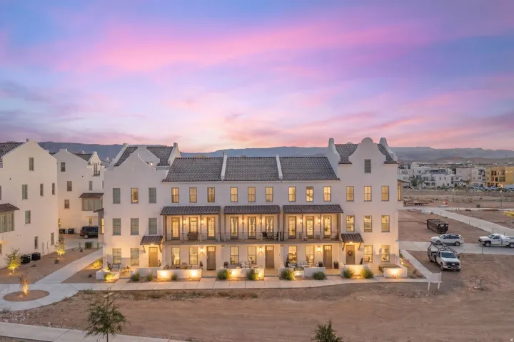White stucco exterior with multiple levels, dark tile roofing, covered balconies, and exterior lighting fixtures
