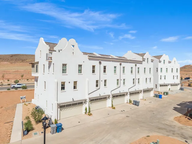 Stucco exterior with multiple private garages, arched pergolas, and a covered balcony