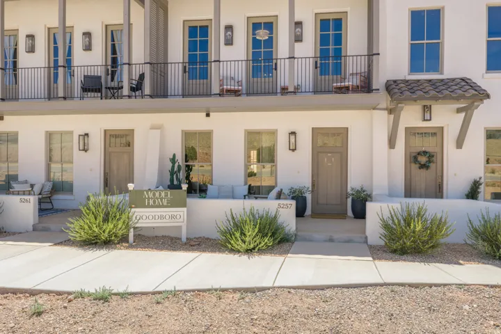 Stucco exterior with multiple balconies, wood-finish doors, wall-mounted exterior lighting, and a tile-covered portico