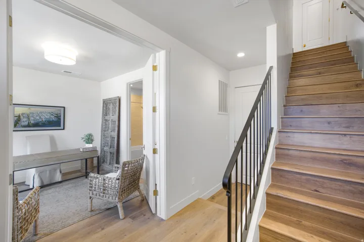 Hardwood flooring, white walls, and a wood-finish staircase with wrought iron railing