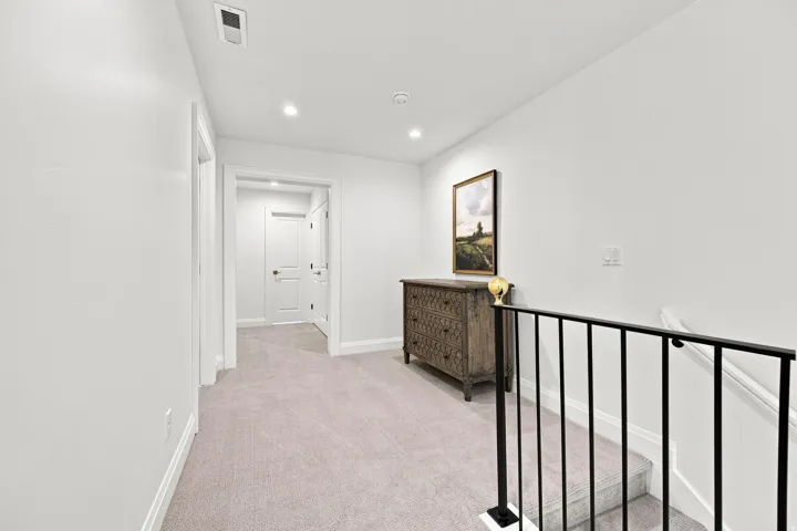 Recessed lighting, light-toned carpet, white walls, white trim, and black metal railing