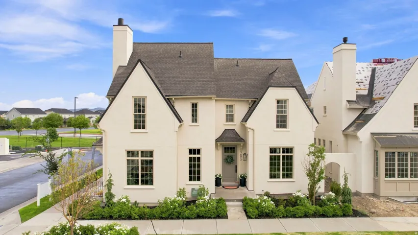 Stucco exterior with multiple gables, dark shingle roof, and prominent chimneys