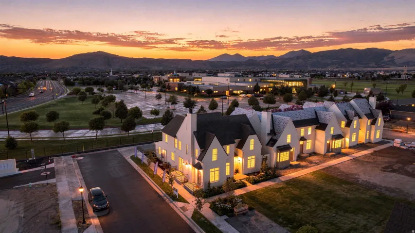 Row of townhomes featuring white exteriors, dark roofs, and multiple windows