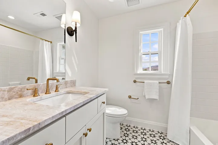 Vanity with integrated sink, brass fixtures, and a stone countertop