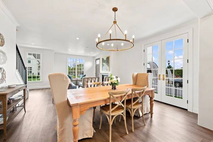 Open-concept living space with wood-finish flooring, a contemporary chandelier, and white French doors