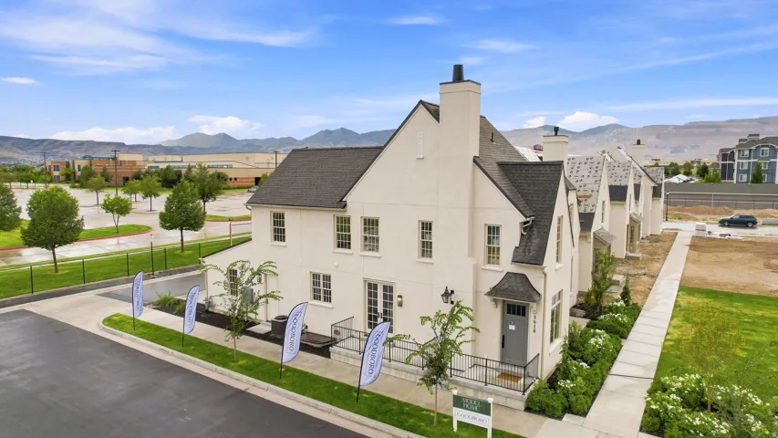 White stucco exterior with a dark shingle roof, multiple chimneys, and prominent gables
