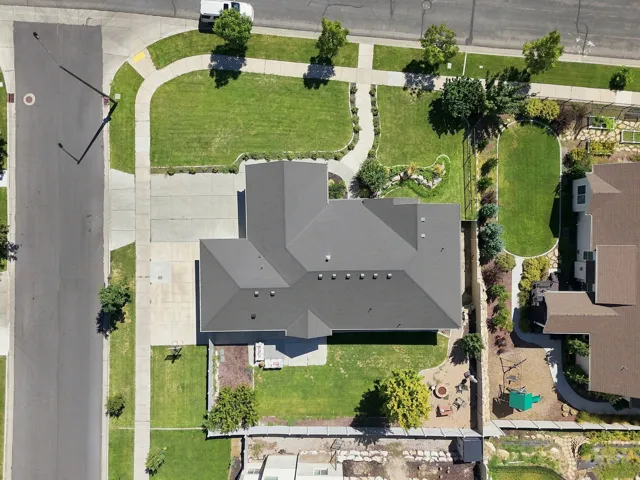 Expansive lot with a sizable driveway, manicured front lawn, and established landscaping