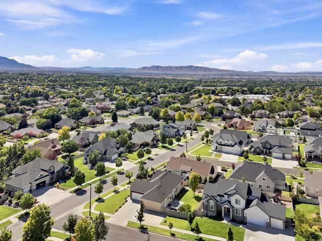 Suburban neighborhood featuring residential homes, mature trees, manicured lawns, and paved streets