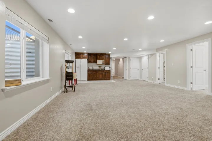Expansive carpeted area with recessed lighting, a window, and multiple white panel doors *without virtual staging*