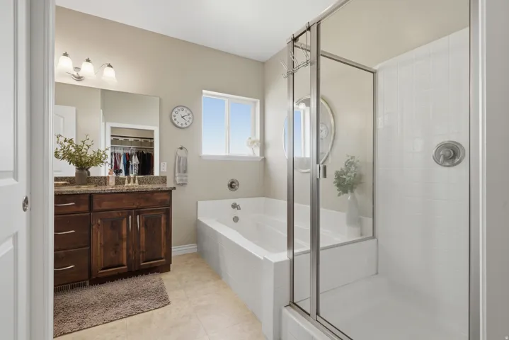 Built-in bathtub and shower with glass enclosure, wood-finish vanity with countertop, and recessed lighting